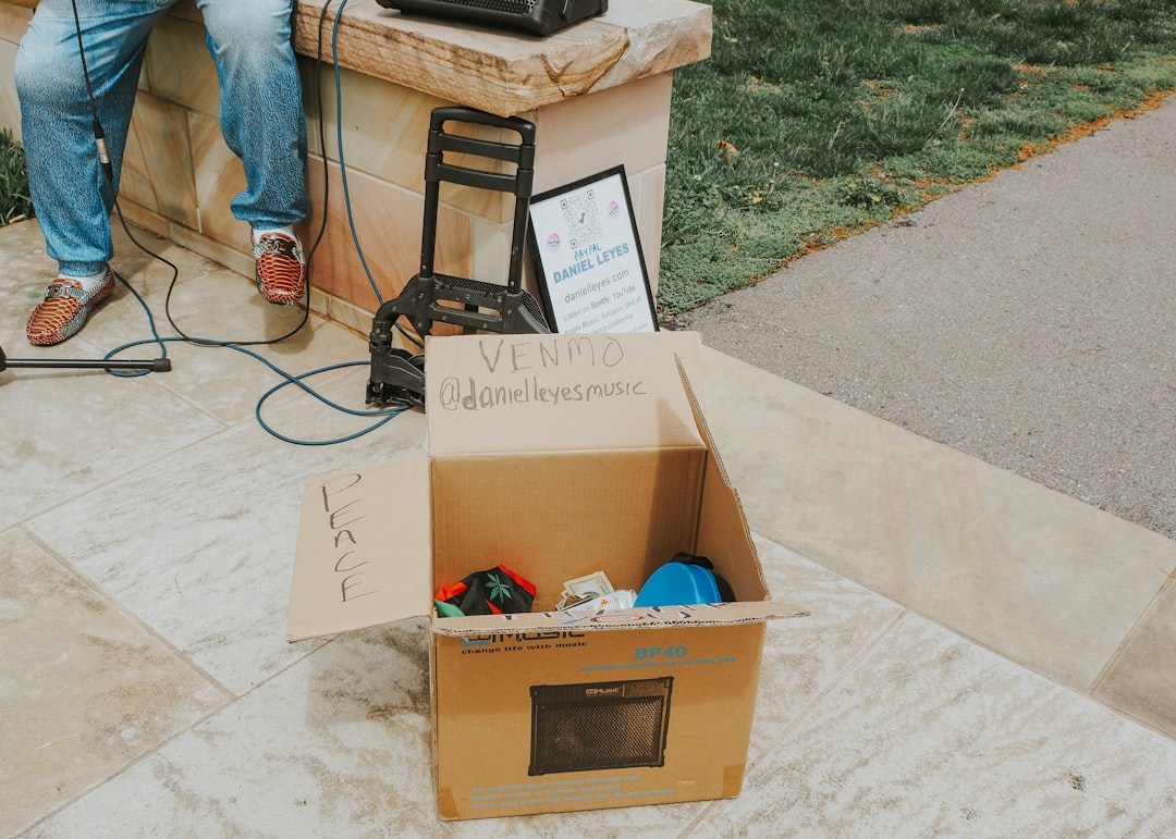 A donation box sits near a street performer.