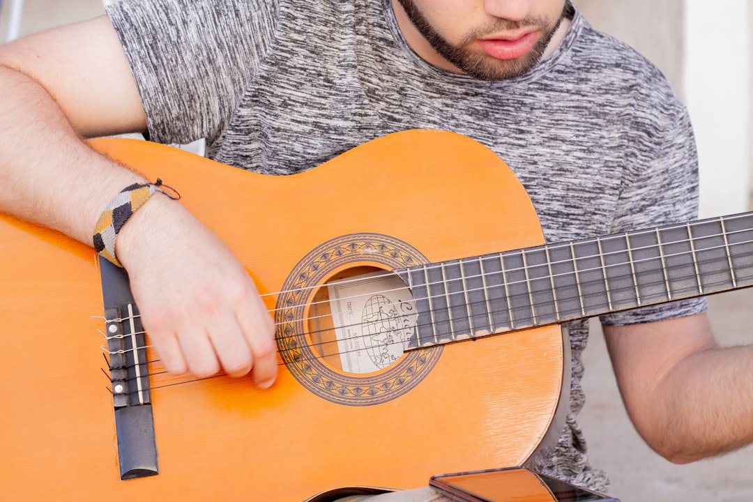 Man playing guitar by Custom Song a man holding an orange guitar in his right hand