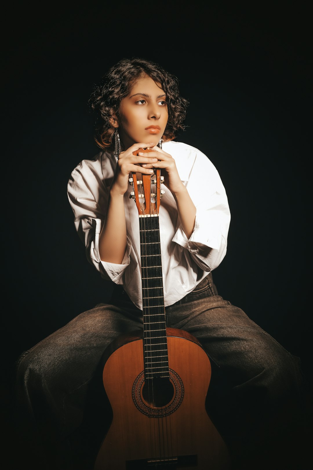 FAQ by Custom Song Girl poses thoughtfully with a classical guitar.